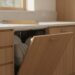 Vestavná myčka pod pracovní deskou v kuchyni se dřevěnými skříňkami a pootevřenými dvířky